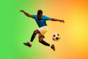 Male soccer, football player training in action isolated on gradient studio background in neon light
